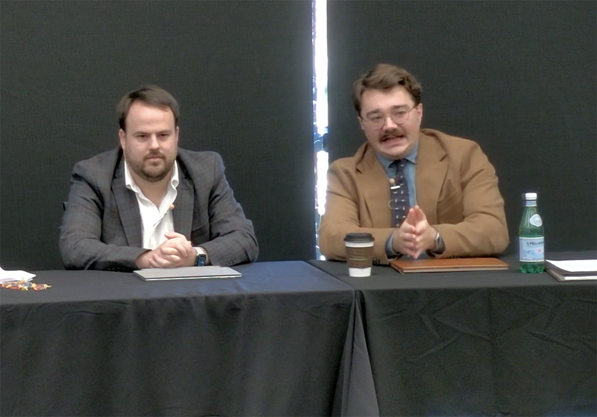 Panelists, two men at a table