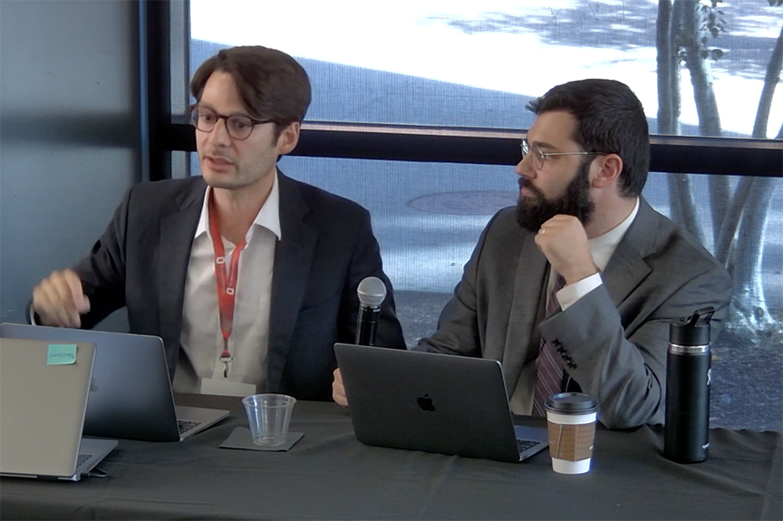 Panelists, two men at a table