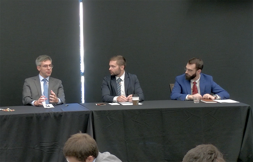 Panelists, three men sitting at a table
