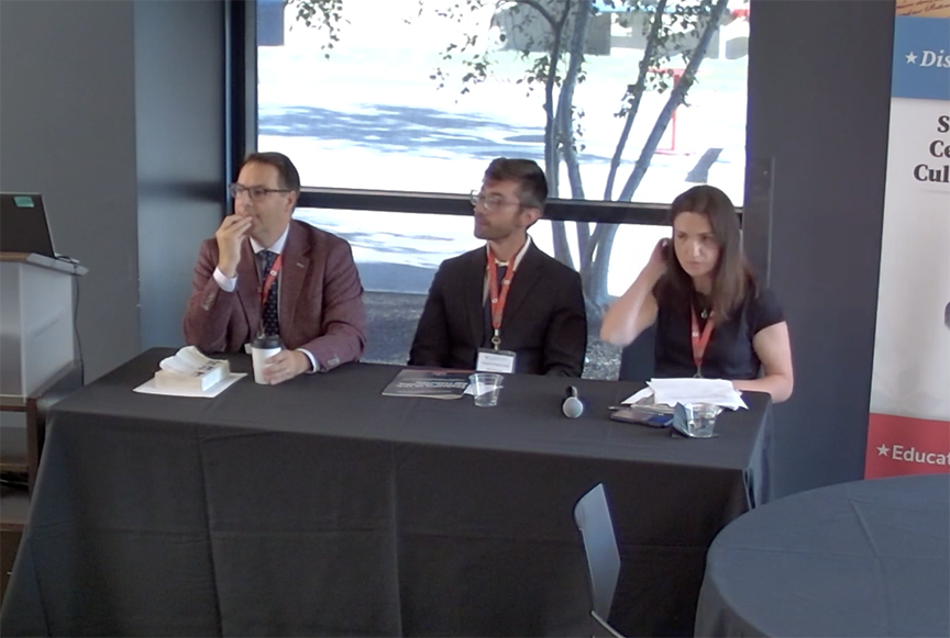 Panelists, two men and a woman at a table