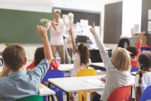 children raising hands in classroom